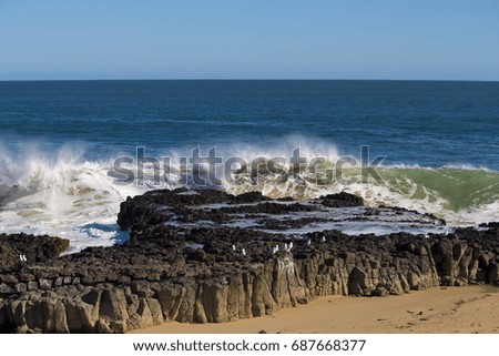 Spectacular foamy backwash from the  Indian Ocean waves breaking on basalt rocks at  Ocean Beach Bunbury Western Australia on a sunny morning in mid winter sends salty spray high into the air.