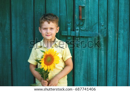 A boy with a bouquet of sunflowers on a background of an old door . Flowers for mom
