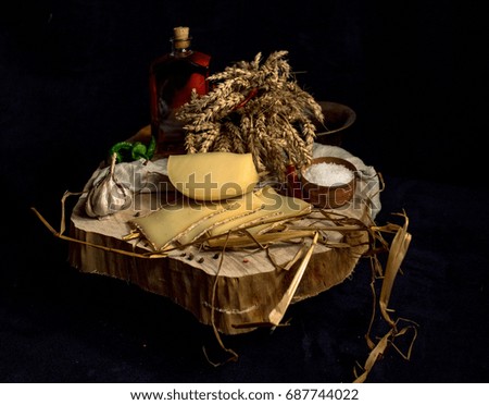 Homemade cheese on the dark background with vegetables with bottles on wood table