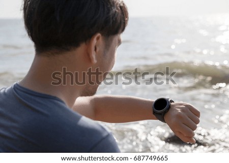 Asian man check his smart watch on the beach.
