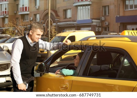 Handsome man talking to female taxi driver through opened window