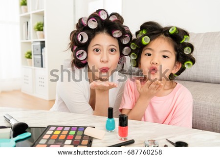 cute young little girl kid with beautiful mother making kiss mouth and showing palm blowing to camera when they makeup together at home.