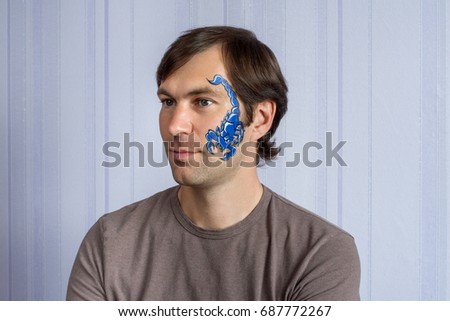 Young man with face painting blue Scorpio mask
