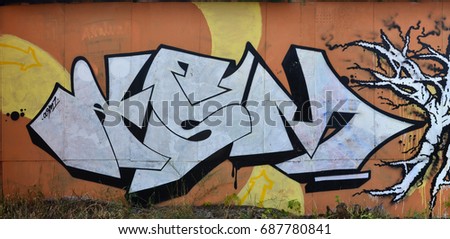 A photograph of a detailed wall artwork. Graffiti drawing is made with white paint with black outlines and has a monophonic orange background. Texture of wall with graffiti decoration