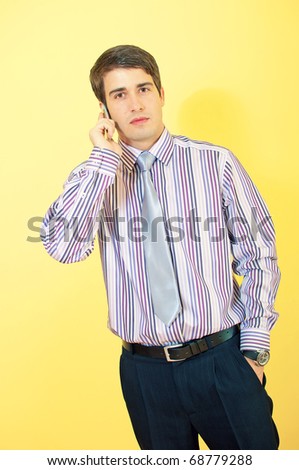 A young trendy attractive european businessman with a cellphone calling over uniform background