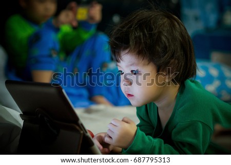 asian children watching tablet on bed / dark tone color
