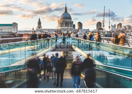 London and St Paul Cathedral at sunset, with blurred people walking on the bridge. Long exposure image with crowd visiting London. Travel, tourism and architecture concepts