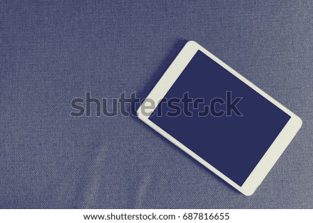 Tablet computer on sofa texture background and blank screen. Top view, concept of technology and device digital.