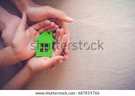 Adult and child hands holding green paper house, eco house, family home, house insurance concept, zero waste, green sustainable living, social distancing, homeschool