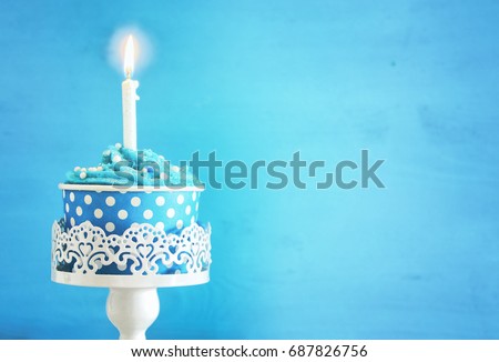 Birthday concept with cupcake and one candle on wooden table.