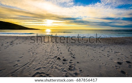 Footsteps tracks in sand on beach with sunrise or sunset. Tracks in the sand with the ocean in the background. Atlantic ocean, Galicia Spain. Background wallpaper picture.