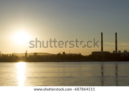 Pipe factory against the background of the river sunset