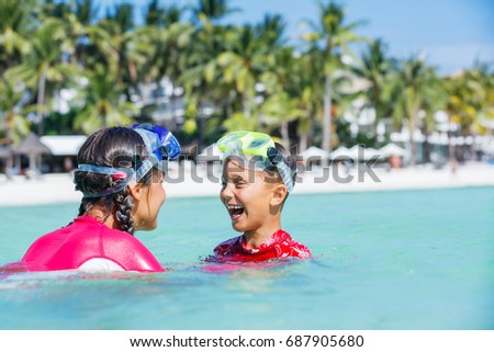 Happy boy and girl playing in the sea. Kids having fun outdoors. Summer vacation and healthy lifestyle concept
