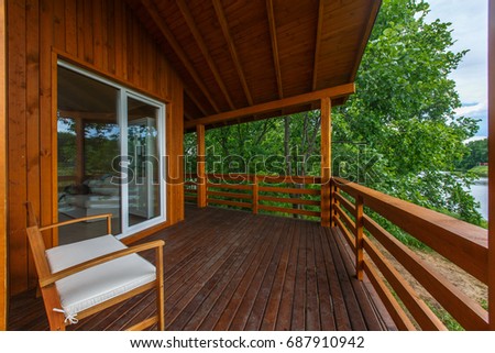 Wooden terrace of wooden house. Yellow wooden planking. Panorama windows. Outside furniture. Perfect view on oak forest. Royalty-Free Stock Photo #687910942
