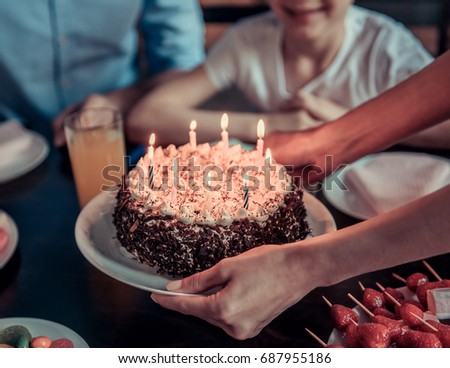 Family celebrating birthday. Cropped image of mom holding a birthday cake with candles