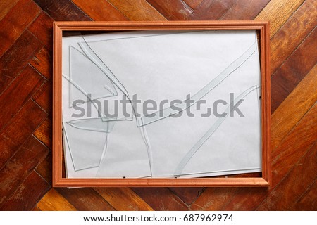 Wooden photo frame with broken glass lies on the floor