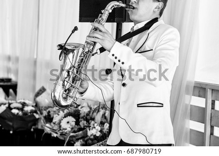 Saxophonist in white jacket playing the saxophone. Saxophonist jazz man with saxophone on wedding party