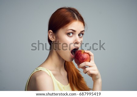 Woman biting an apple on a gray background diet, losing weight                               