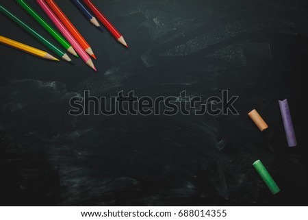 Top view / Flat lay the color pencil and colorful chalk board on black table wooden background.Space for free creative design word or text.Education or back to school concept.above or overhead.