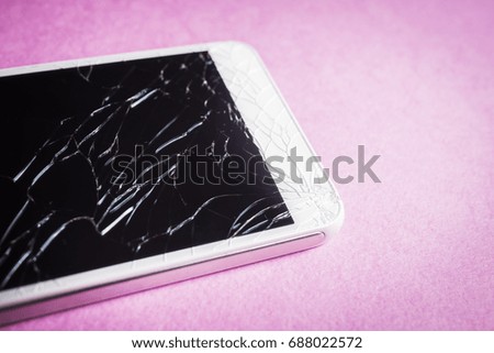Broken mobile phone on a pink background