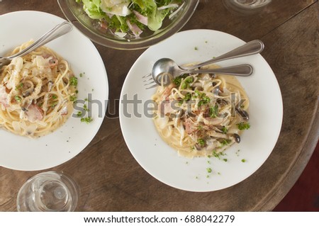 top view of table of lunch cream pasta with salad and glass of water.