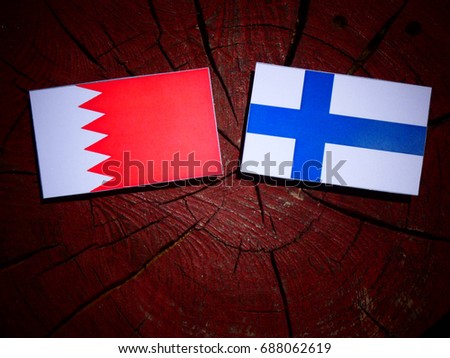 Bahraini flag with Finnish flag on a tree stump isolated