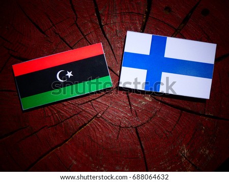 Libyan flag with Finnish flag on a tree stump isolated