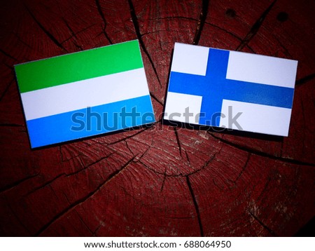Sierra Leone flag with Finnish flag on a tree stump isolated