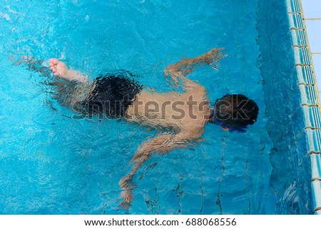 A boy learning swim in swimming pool.Asian boy under the water between swim class.