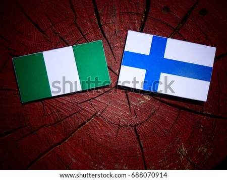 Nigerian flag with Finnish flag on a tree stump isolated
