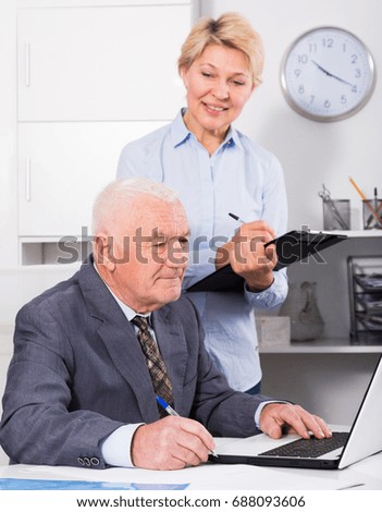 Aged manager and secretary working productively together in office