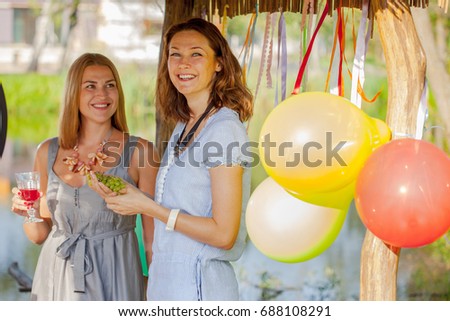Two beautiful cheerful women at a picnic party near the lake