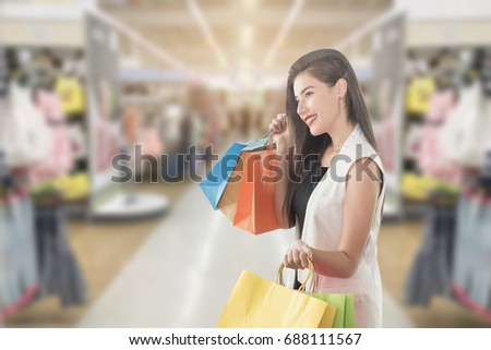 Selective focus of beautiful woman holding shopping bag and over blurred image of shopping mall.