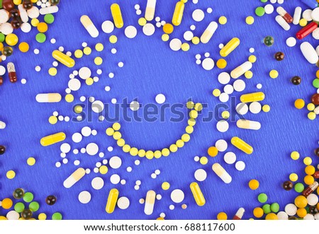 Many different colorful medication and pills from above in the shape of sun on a purple background