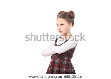 Portrait of offended girl in school uniform standing cross-armed against white background