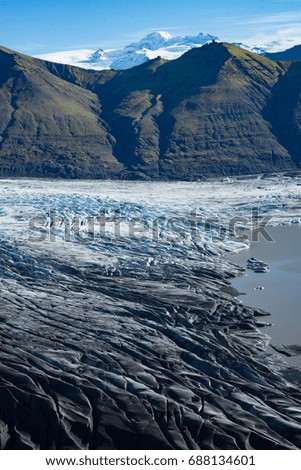 Glacier in Iceland with mountain backdrop - Glacier color changes from dark black to icy blue to white. High resolution, great picture to zoom in.
