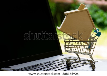 Model wooden house in mini shopping cart on Laptop. 
Can advertisement or montage product and business.
Image for property real estate investment concept. 
Homes for sale in market.
Selective focus. 
