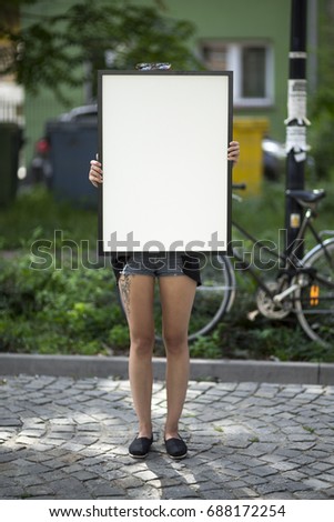 Girl holds a frame on the street for a poster presentation