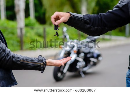Hands pass the keys to the motorbike.
