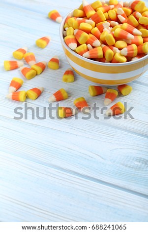 Halloween candy corns in bowl on blue wooden background