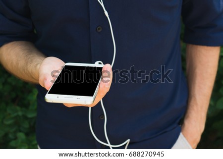 man, using a smart phone and headphones in the hands, background, with copy space, free space, for advertising