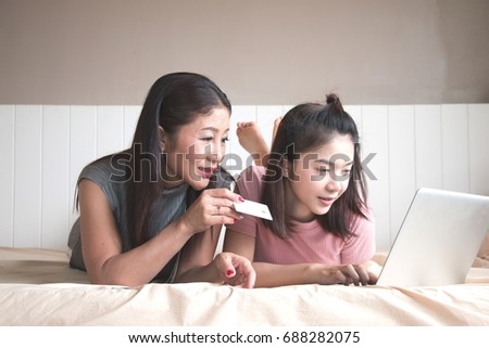 Mother and daughter is using computer in the family for buying thing on line