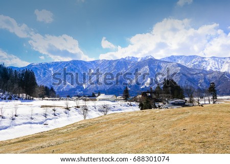 Hakuba mountain range  and  Hakuba village houses  in the winter with snow on the mountain and blue sky and clouds background in Hakuba  Nagano Japan.