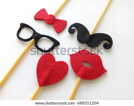 Top or flat lay view of Photo booth props heart shape, lips, spectacles, bow tie and mustache on a white background flat lay. Birthday parties and weddings.

