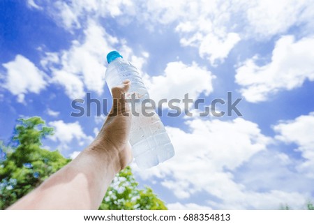 A man showing the cold water bottle in to the sky.