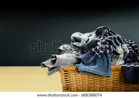 Laundry basket.Full of clothes in a wicker basket on dark background.
