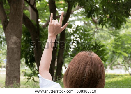Female hand with I love you finger gesture. woman showing symbol sign language in the park