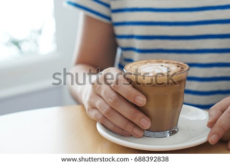 Hand holding hot mocha A Cup of Coffee with Beautiful Latte Art on wooden table background and copy space, Morning Breakfast, Selective Focus.