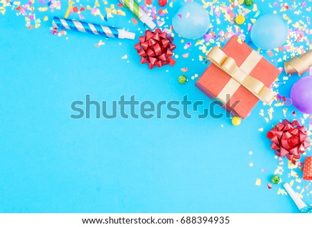 Red gift box various party confetti, balloons, on blue background with border. Flat lay. Colorful celebration pattern