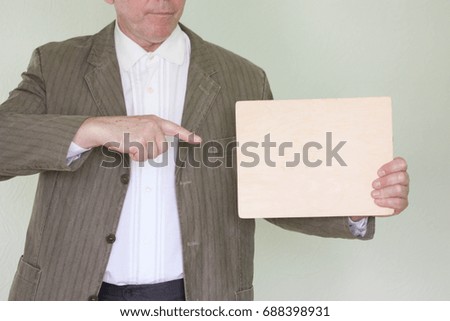 Business concept businessman. Holds an empty nameplate. Point with your finger. In the profile. Place for your text. Photo for your design